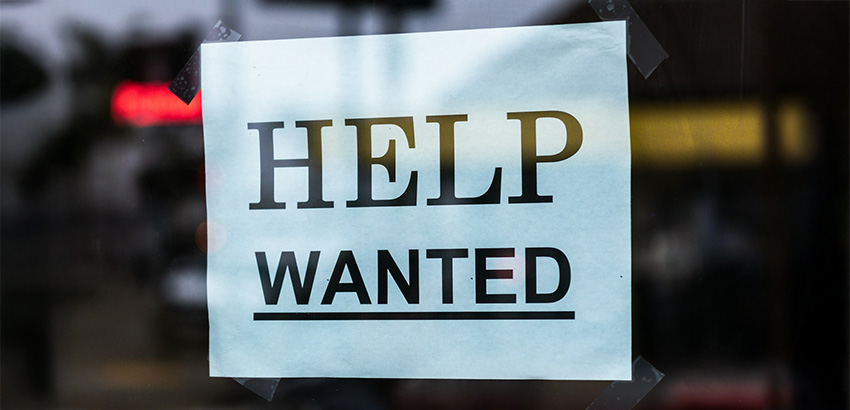 Zettel hinter einer Glasscheibe mit den Worten "Help wanted".