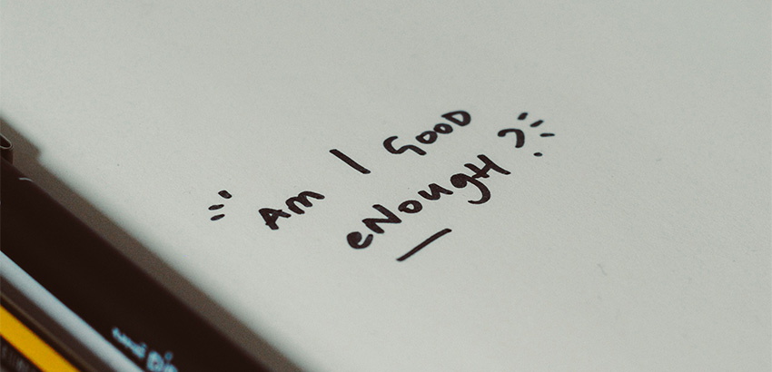 Notizbuch, in welchem handschriftlich geschrieben steht "Am I good enough?"
